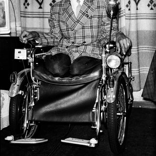 Man in wheelchair attached to motorcycle.