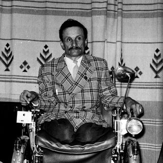 Man in wheelchair with motorcycle seat.