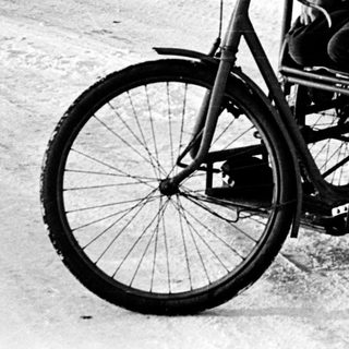 Child riding a tricycle in snowy outdoor setting.