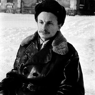 Man in winter attire posing outdoors in snowy setting.