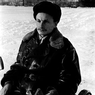 Man in winter attire sitting on horse in snowy outdoor setting.