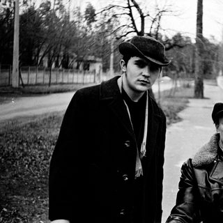 Two men in vintage winter attire walking outdoors.