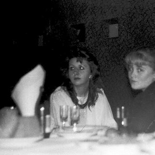Blurred black-and-white indoor group at dimly lit table.