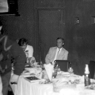 Formal dinner gathering with seated man speaking.