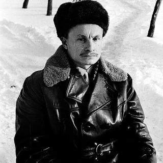 Man in winter attire standing outdoors in snowy park.