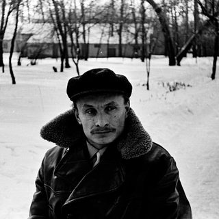 Man in winter attire standing in snowy park.