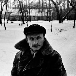 Man in winter attire standing in snowy park.