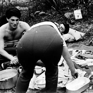 People camping, preparing food outdoors.