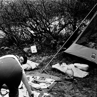 People camping, preparing food outdoors.