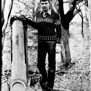 Young man posing outdoors near tree stump.