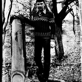 Young man posing outdoors near old chimney.