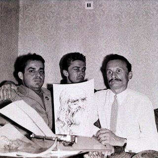 Three men examining a portrait sketch indoors.