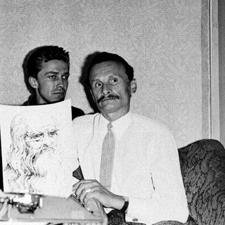 Three men holding a portrait sketch indoors.