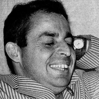 Man smiling while leaning on a chair.