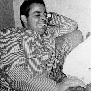 Man smiling while leaning on a chair.