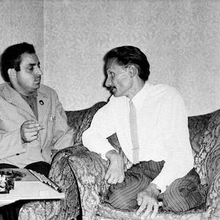 Two men engaged in conversation indoors.