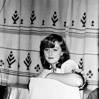 Young woman holding vintage-style white dress.