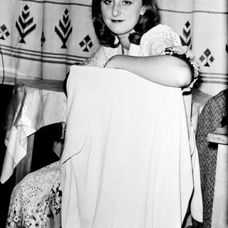 Young woman holding vintage-style white dress.