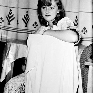 Young woman holding vintage-style white dress.