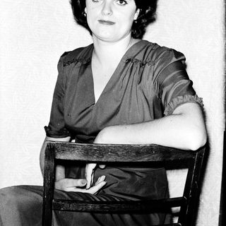 Woman in 1930s-40s style dress posing indoors.