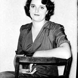 Woman in 1930s-40s style dress posing indoors.