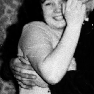 A couple hugging indoors, mid-20th century.