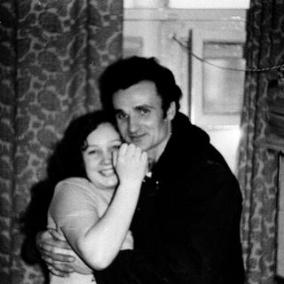 A couple hugging indoors, mid-20th century.