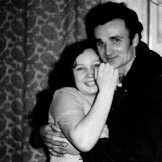 A couple hugging indoors, mid-20th century.