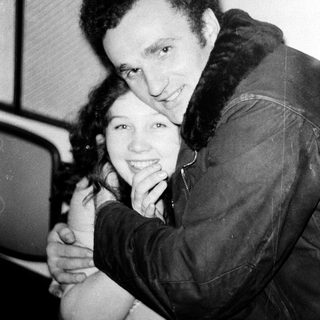 Two people hugging affectionately indoors.