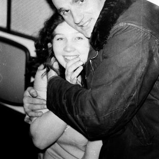 Two people hugging affectionately indoors.