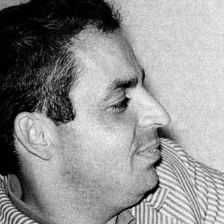 Man in striped shirt posing thoughtfully, smoking.