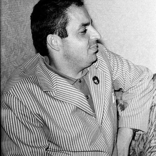 Man in striped shirt posing thoughtfully, smoking.