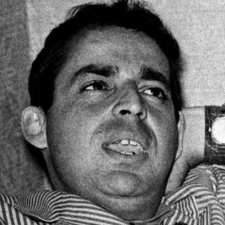 Man in striped shirt leaning on armrest.