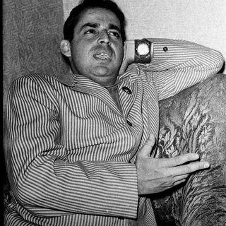 Man in striped shirt leaning on armrest.