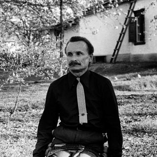Man sitting outdoors in vintage attire.