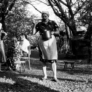 Rural women outdoors in traditional attire, preparing food.