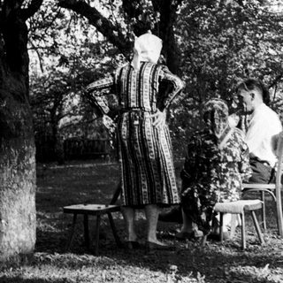 Rural women outdoors in traditional attire, preparing food.