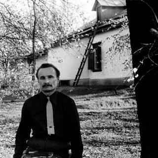 Man sitting outdoors in vintage black-and-white photograph.