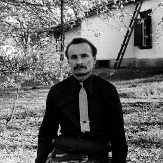 Man sitting outdoors in vintage black-and-white photograph.