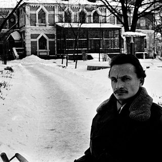 Man in winter coat posing outdoors on snowy path.