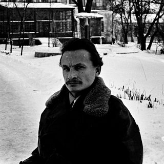 Man in winter coat posing outdoors on snowy path.