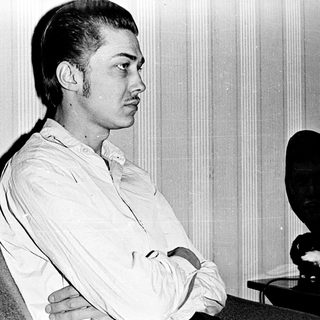 Young man sitting pensively in an indoor setting.