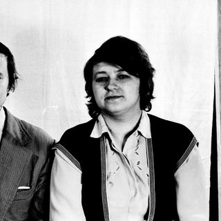 Two individuals in 1970s-style formal attire posing together.