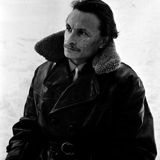 Man in winter coat standing in snowy outdoor setting.