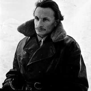 Man in winter coat standing in snowy outdoor setting.