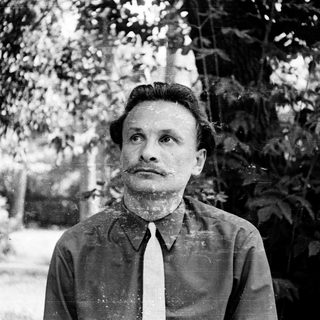 Man in vintage attire standing outdoors, looking upward.