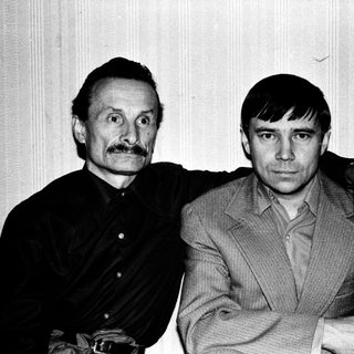 Two men posing together in a candid black-and-white photo.