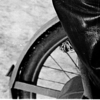 Man in winter attire sitting on bicycle in snowy outdoor setting.