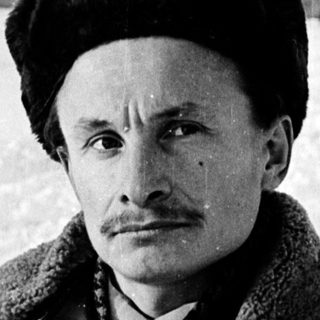 Man in winter attire posing outdoors in snowy setting.