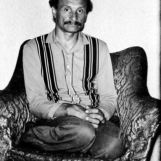 Man in striped shirt seated on armchair.